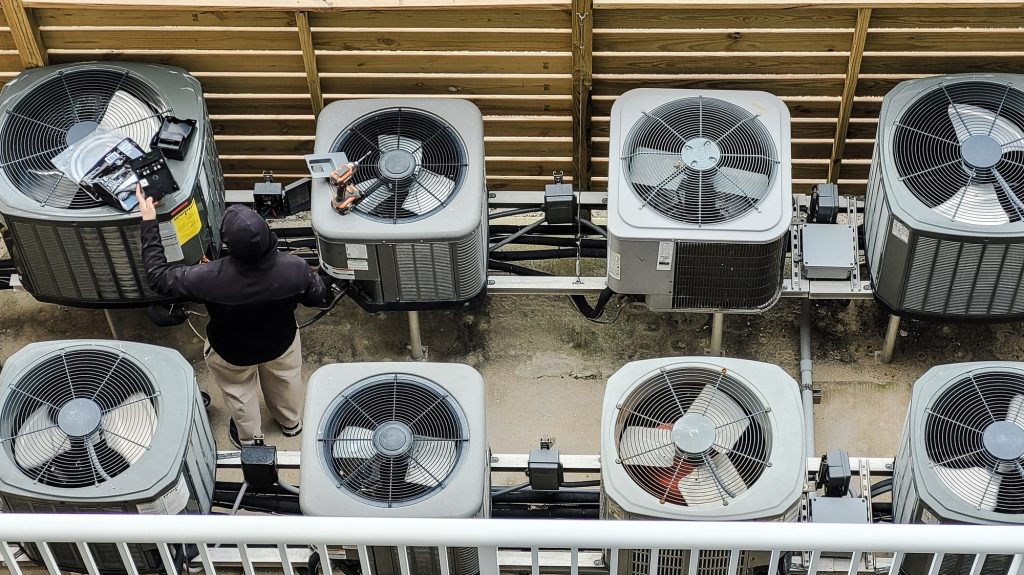 HVAC technician using modern technology instruments to analyze HVAC units in beach condo.