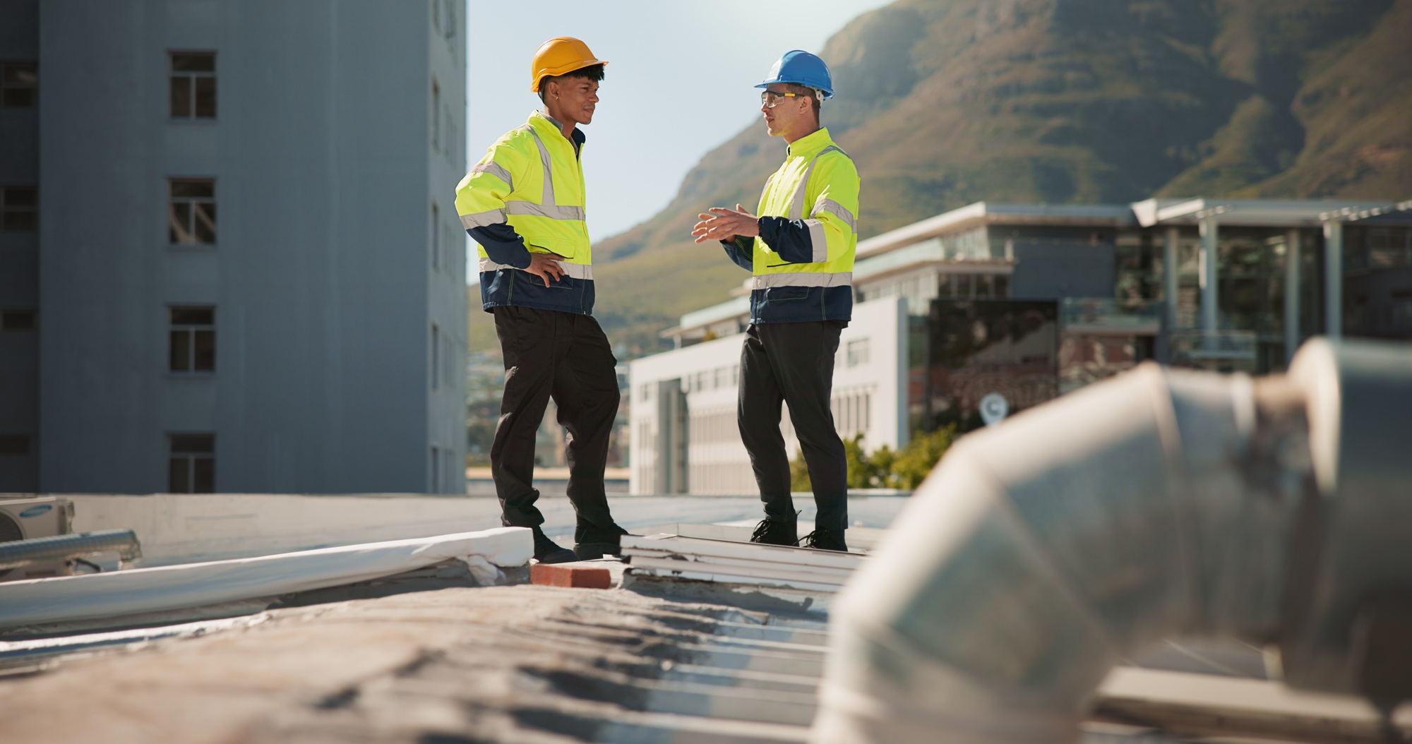 Teamwork, engineering and contractor with people on rooftop for construction, discussion or hvac te